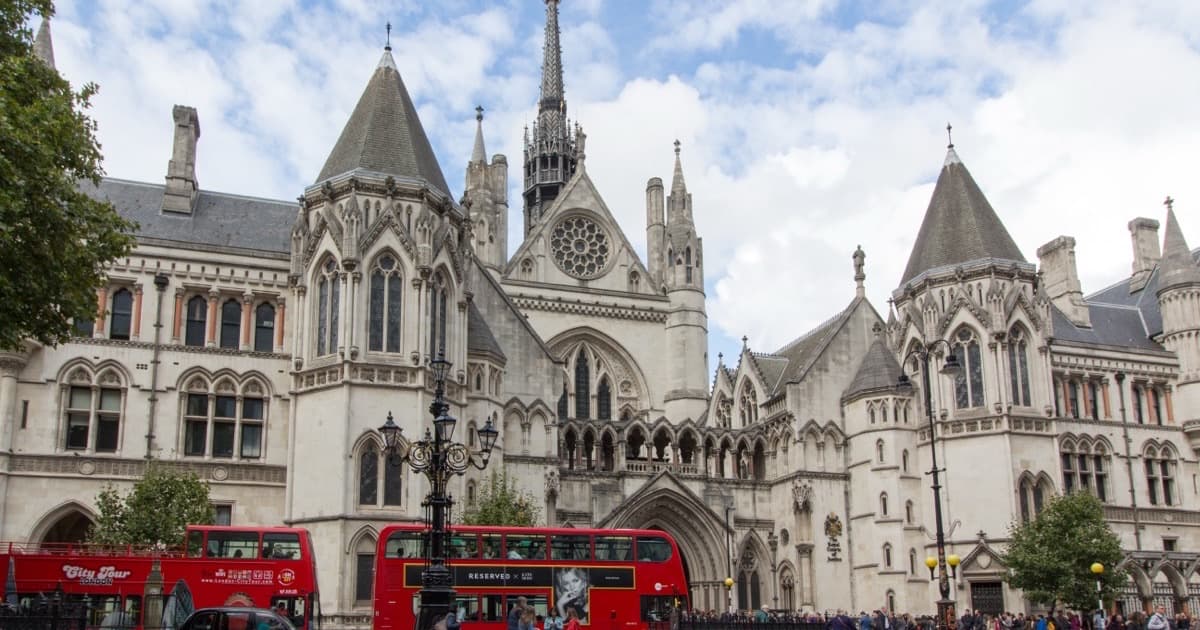 The Royal Courts of Justice on the Strand in London, with a red double decker bus passing
