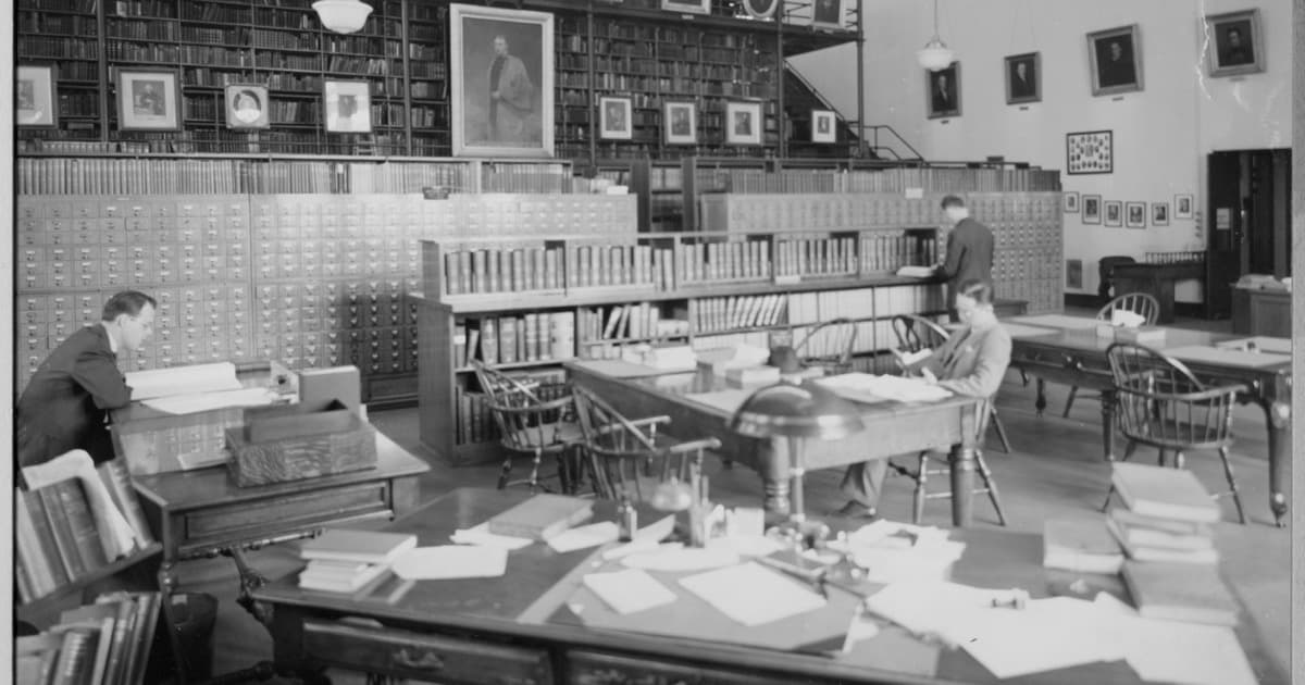 Readers at desks working through journals and papers in the reading room of a medical library